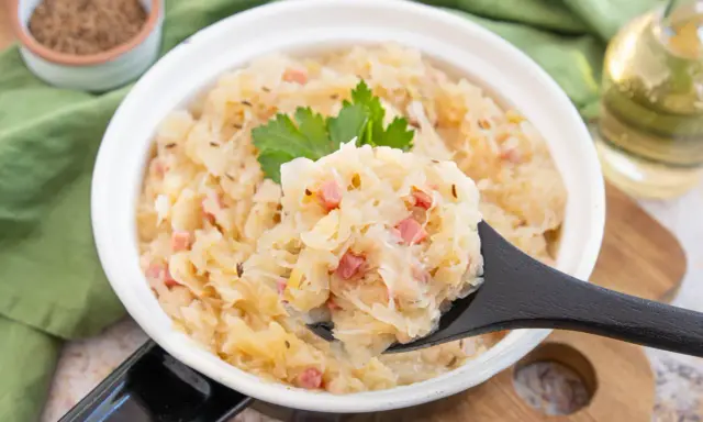 Herzhaftes Sauerkraut nach Hausfrauenart mit Speck und Kümmel, garniert mit Petersilie. Ein Löffel voller Tradition.