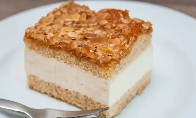 Ein Stück Kuchen mit cremiger Füllung und karamellisierten Mandeln. Der Kuchen wird zu dunkel, aber die Mandeln sind perfekt gebräunt.