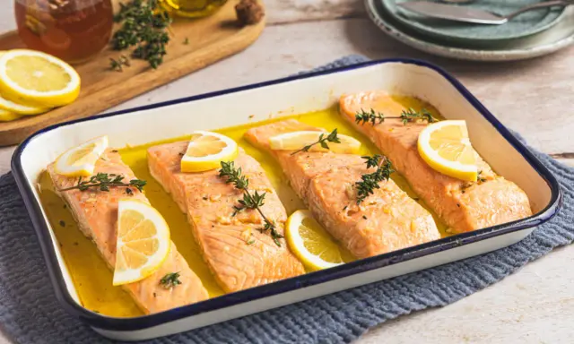 Vier Lachsfilets mit Zitrone und Thymian in einer Auflaufform, bereit für den Ofen. Perfekt für einfache Lachs Rezepte Ofen.