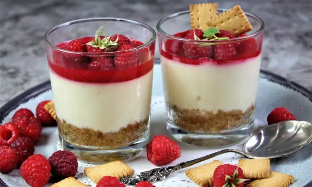 Zwei leckere Desserts im Glas mit Himbeeren und Keksen, ein Genuss für Augen und Gaumen.