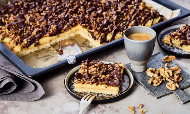 Ein Stück "friss dich dumm Kuchen" mit Schokoladen-Nuss-Decke und einer Tasse Kaffee.