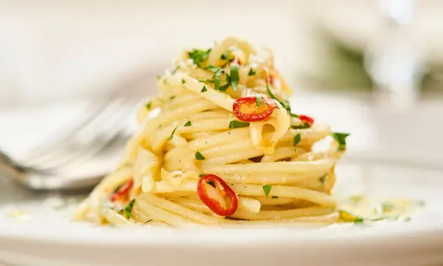 Ein Berg von Spaghetti Aglio e Olio, garniert mit frischer Petersilie und scharfen Chilischeiben.