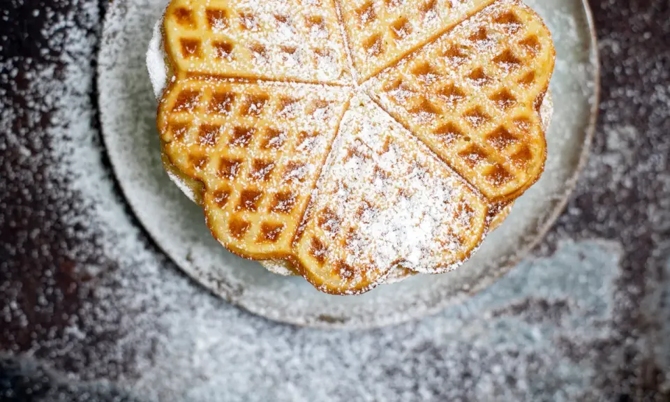 Herzförmige Waffeln, bestäubt mit Puderzucker, sehen aus wie aus einem perfekten Waffeln Rezept.