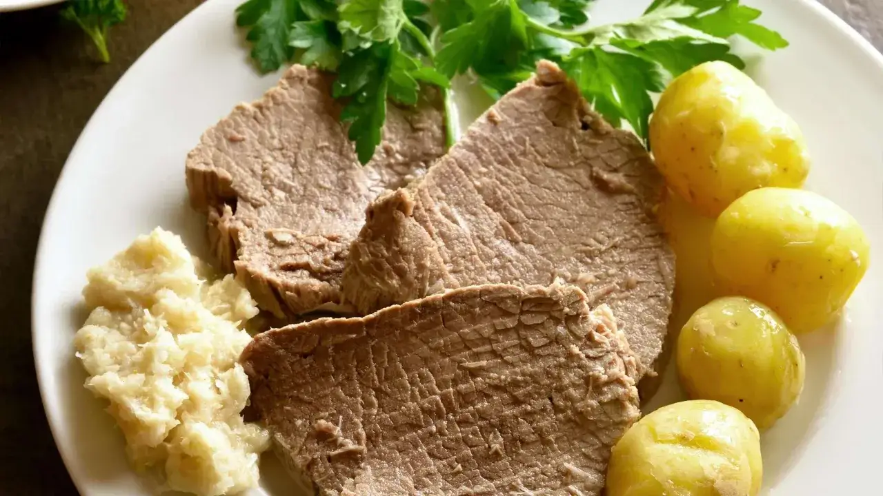 Zarte Scheiben gekochtes Rindfleisch mit Salzkartoffeln und Apfelmus, garniert mit Petersilie. Ein Klassiker zum Rindfleisch kochen.