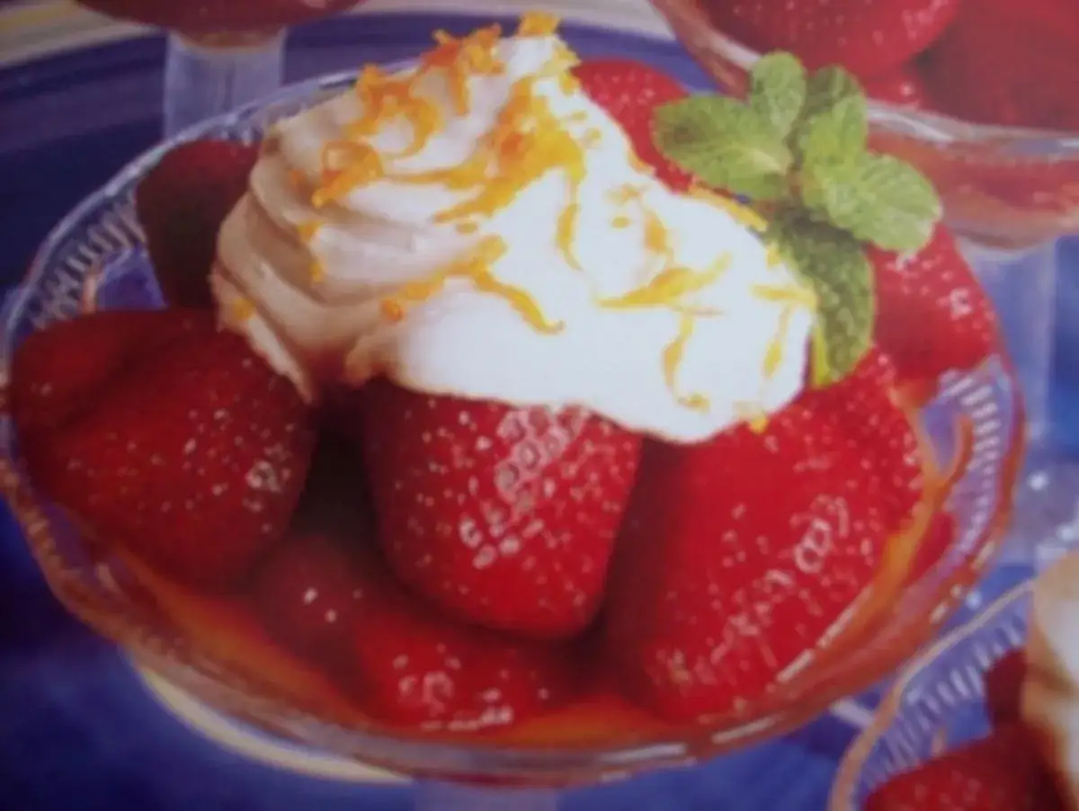 Erdbeeren Romanoff: Frische Erdbeeren in Sirup, gekr&ouml;nt mit Schlagsahne, Orangenzesten und Minze. Ein s&uuml;&szlig;er Genuss.