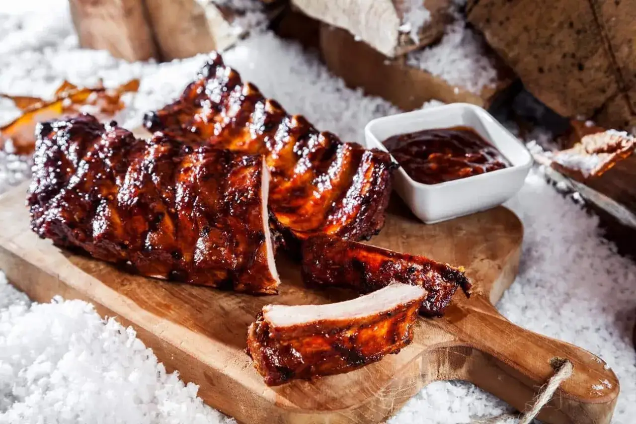 Saftige spareribs backofen, glasiert und mit BBQ-Sauce, auf einem Holzbrett im Schnee.