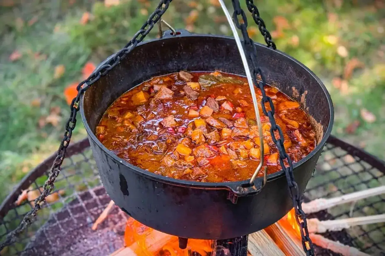 Herzhafte Gulaschkanone Rezepte: Ein deftiger Eintopf k&ouml;chelt &uuml;ber offenem Feuer.
