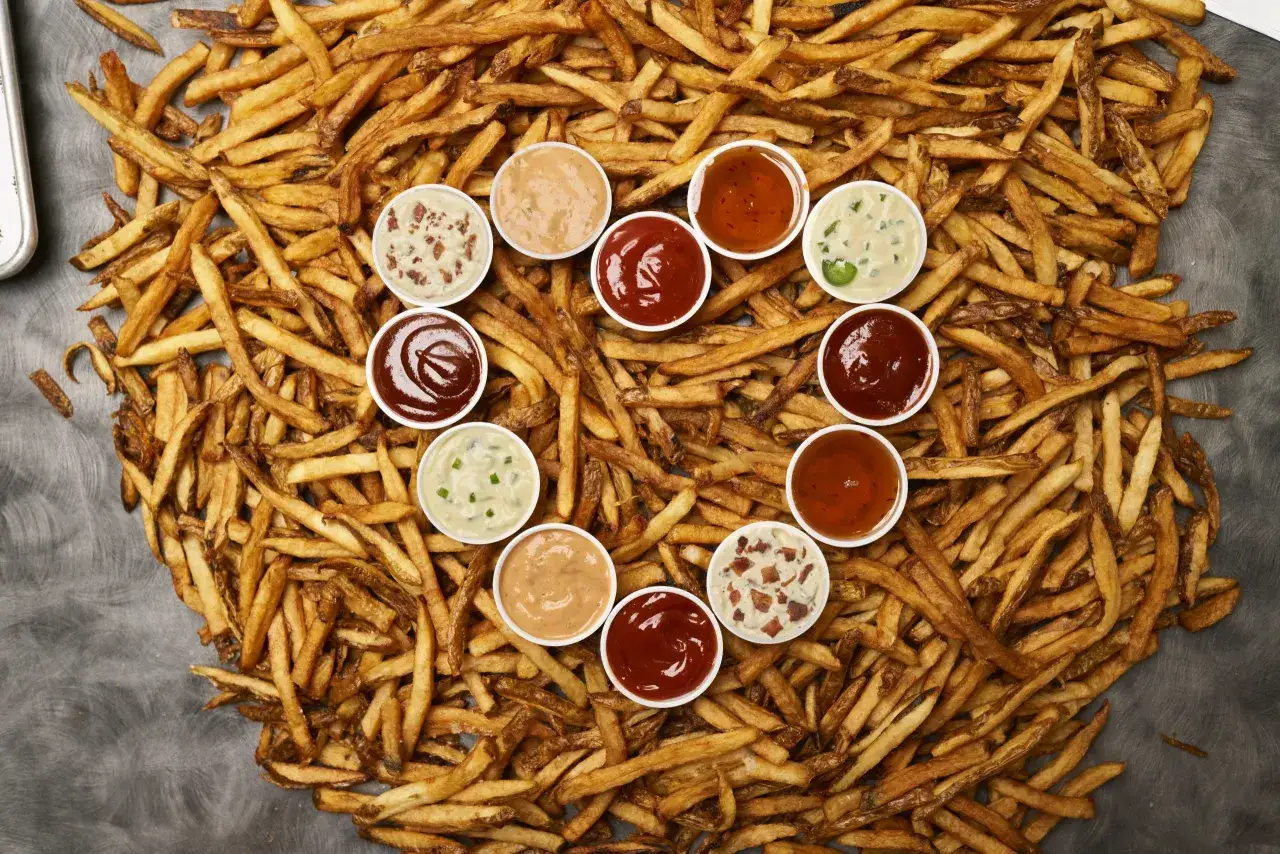 Ein Berg goldbrauner Pommes Frites, umgeben von kleinen Sch&auml;lchen mit verschiedenen Dips. Ein wahres Pommes Spezial f&uuml;r jeden Geschmack!