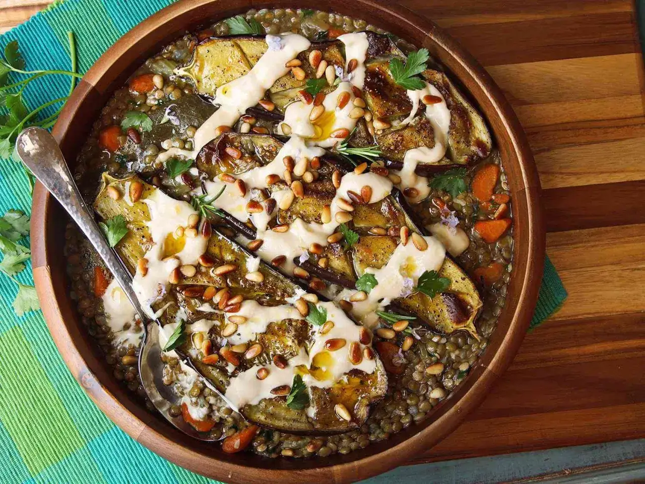 Herzhafte Linsen mit gegrillten Auberginen, Karotten und Pinienkernen, beträufelt mit Tahini-Dressing. Ein köstliches Beispiel für vegetarische Gerichte.