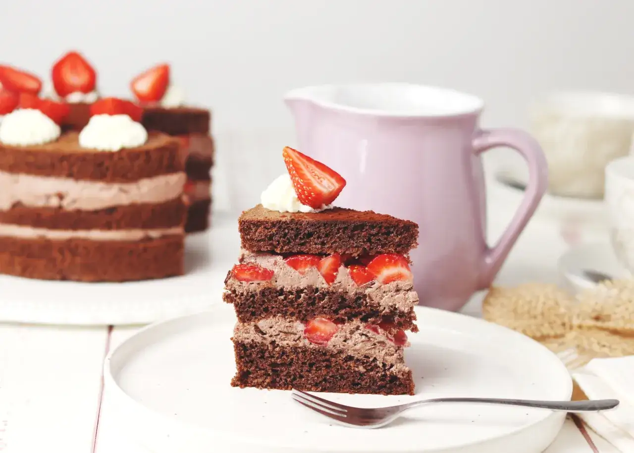 Ein St&uuml;ck saftiger Schokoladenkuchen mit frischen Erdbeeren und cremiger F&uuml;llung, garniert mit einer Erdbeerscheibe. Ein Genuss f&uuml;r jeden Liebhaber von Erdbeerkuchen mit Schokolade.