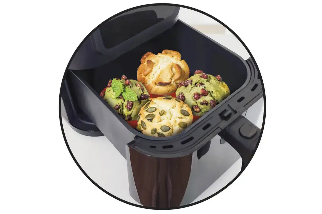 Vier Muffins, zwei mit grüner Füllung und Granatapfelkernen, zwei helle mit Kürbiskernen und Cashews, in einem Philips Airfryer.