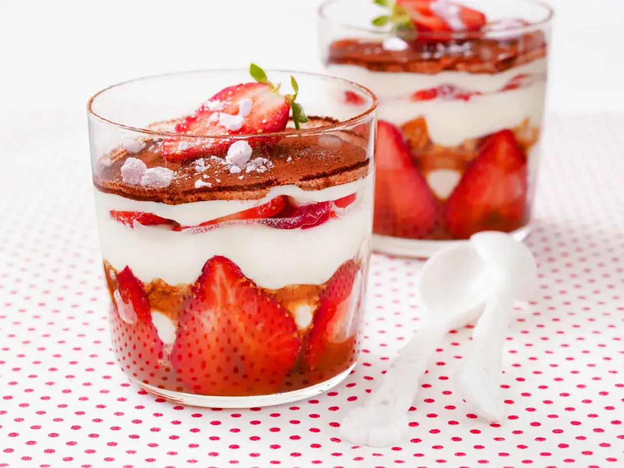 Zwei Gl&auml;ser mit Erdbeer Tiramisu, geschichtet mit frischen Erdbeeren, Creme und Kakao.