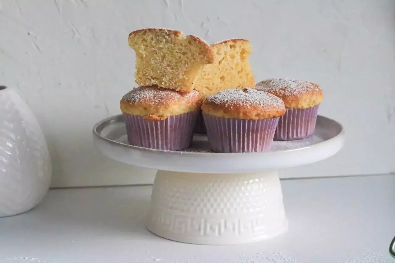 Saftige Muffins, perfekt f&uuml;r jedes Muffins Rezept. Mit Puderzucker best&auml;ubt, auf einem wei&szlig;en Tortenst&auml;nder.