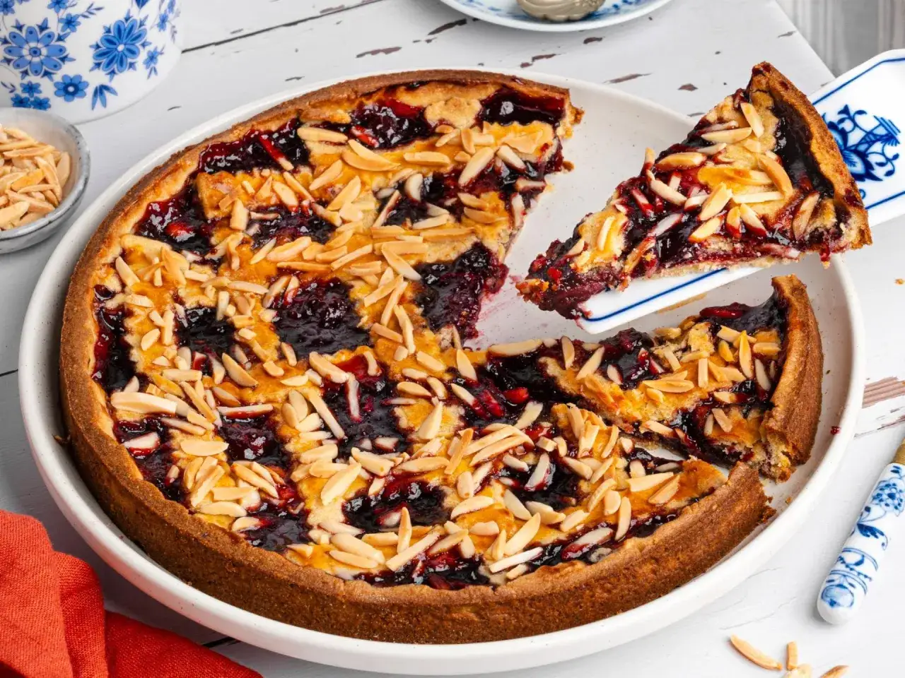Ein k&ouml;stlicher Kirschkuchen mit Mandelbl&auml;ttchen, ein Klassiker unter den beliebte kuchen rezepte. Ein St&uuml;ck wird gerade serviert.