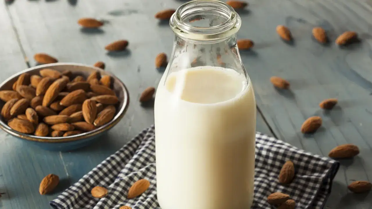 Flasche mit Mandelmilch und Schale voller Mandeln. Ja, kann mandelmilch schlecht werden, wenn sie nicht richtig gelagert wird.
