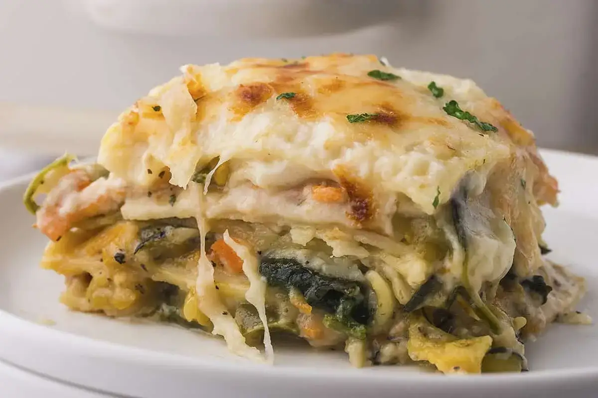 Ein St&uuml;ck saftige vegetarische Lasagne mit geschmolzenem K&auml;se und bunten Gem&uuml;seschichten, garniert mit Petersilie.