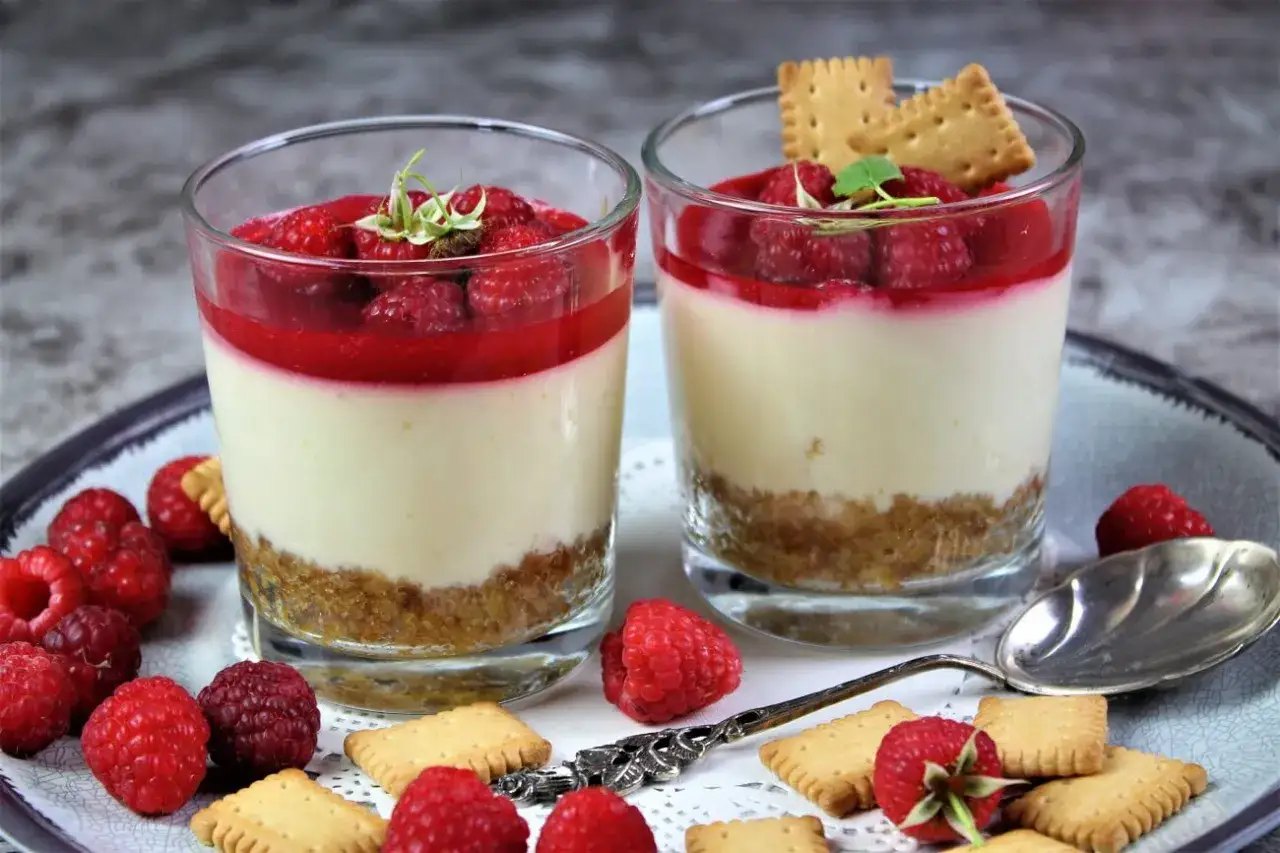Zwei Gl&auml;ser mit einem k&ouml;stlichen Dessert: eine Schicht Keksbr&ouml;sel, cremige Masse und frische Himbeeren. Perfekt, um Kuchenreste verwerten und ein s&uuml;&szlig;es Dessert zu zaubern.