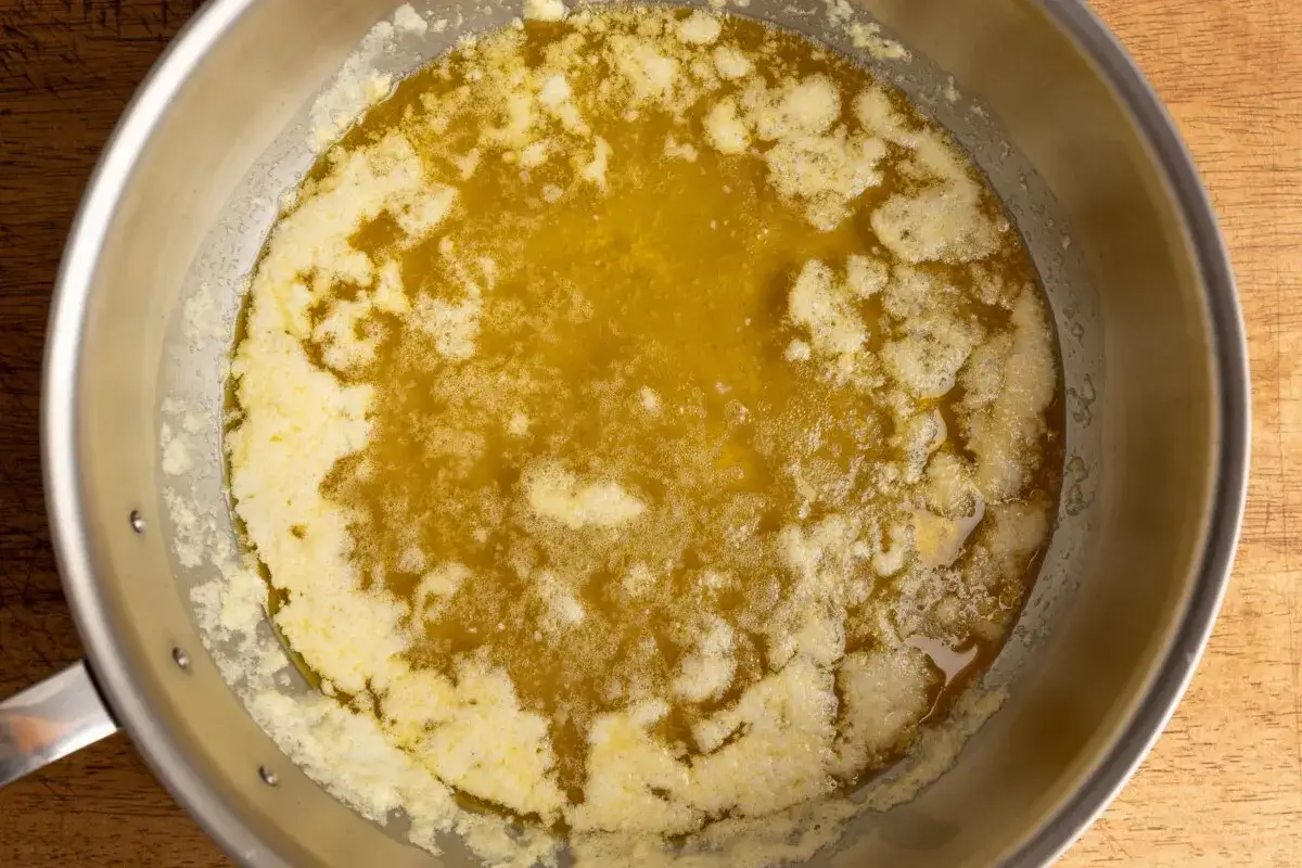 Ghee selber machen: Butter schmilzt in einer Pfanne, Schaum bildet sich.