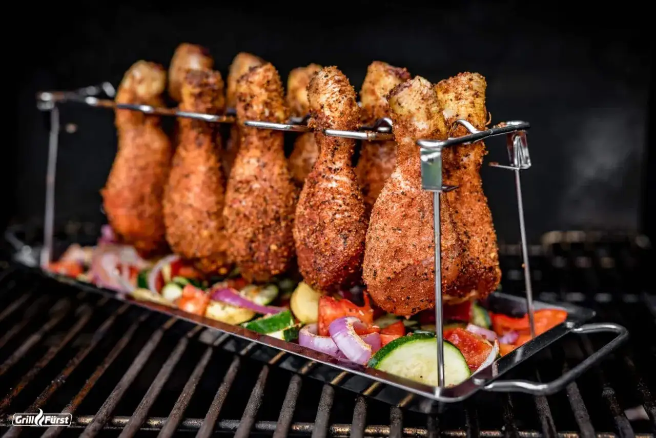 H&auml;hnchenschenkel in einer Gew&uuml;rzmischung f&uuml;r die chicken wings marinade ruhen auf einem Bett aus Gem&uuml;se auf dem Grill.