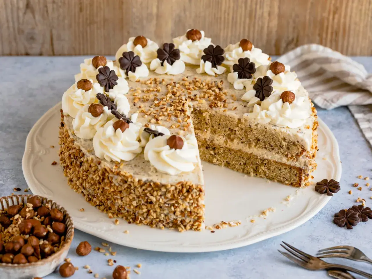 Eine k&ouml;stliche nusstorte mit buttercreme, verziert mit Haseln&uuml;ssen und Schokoladenkleebl&auml;ttern.