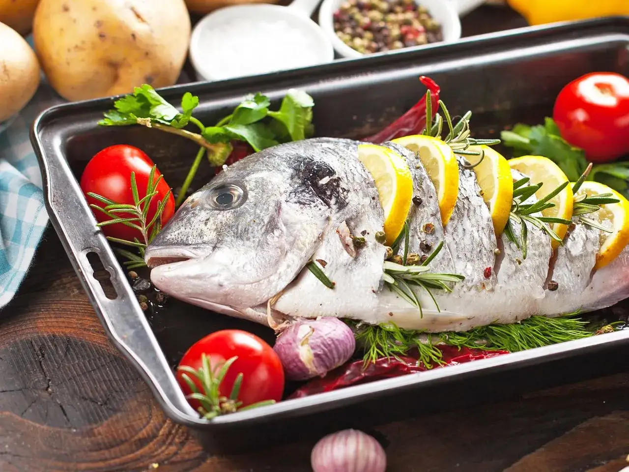 Ein ganzer Fisch mit Zitronenscheiben und Kr&auml;utern in einer Auflaufform. Perfekt f&uuml;r die Frage: wieviel fisch pro person.