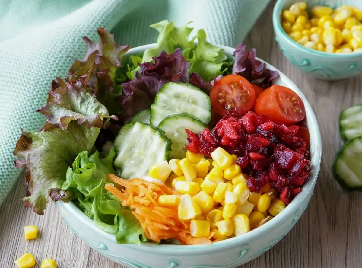 Bunter Salat mit knackigem Kopfsalat, Gurkenscheiben, Tomaten, geraspelten Karotten, Mais und Rote Bete als leckere Beilage.