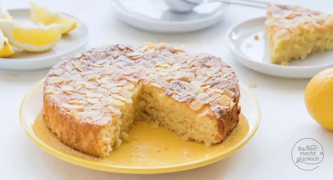 Ein k&ouml;stlicher Kuchen ohne Mehl, bestreut mit Mandelbl&auml;ttchen und Puderzucker, daneben Zitronenspalten.