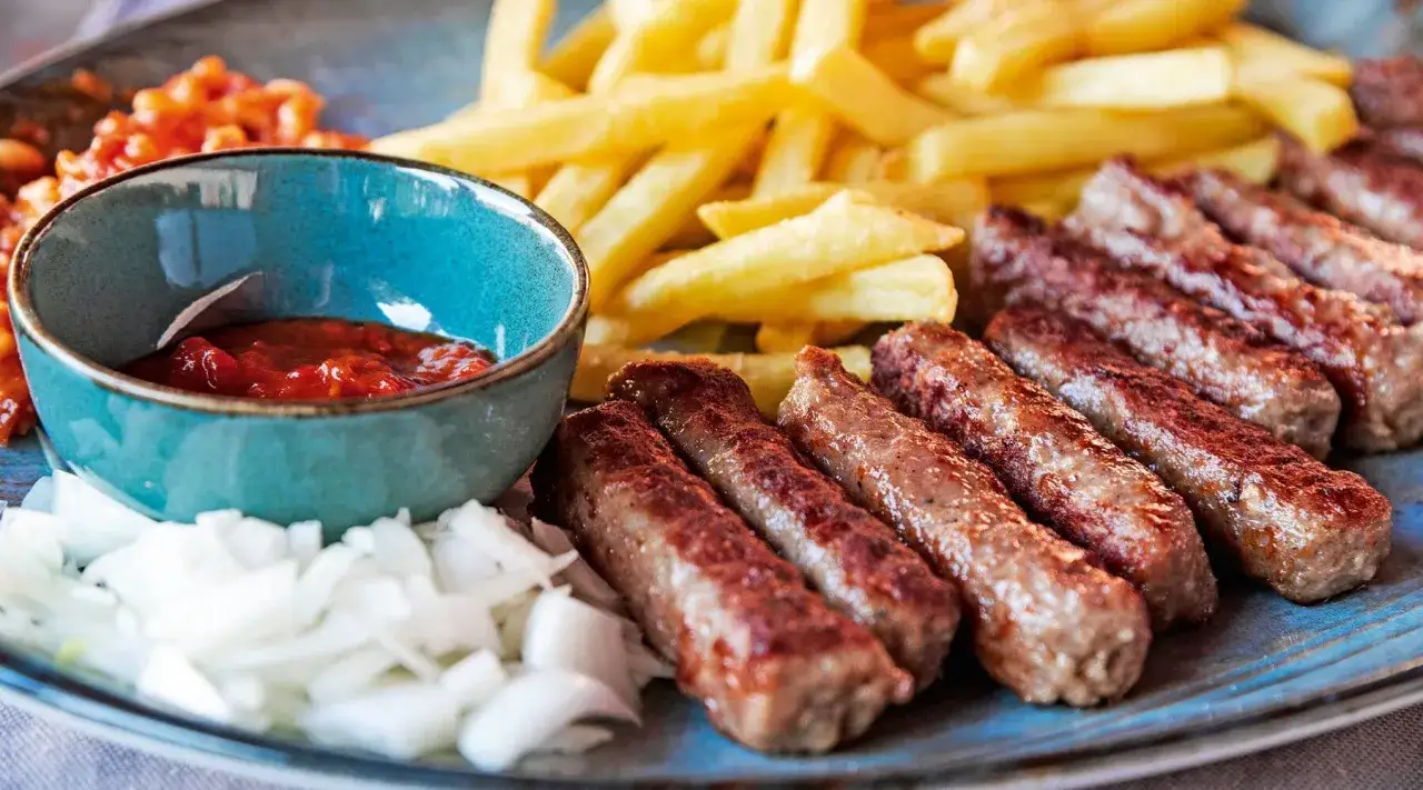 Saftige cevapcici mit knusprigen Pommes, dazu eine Schale scharfer Sauce und frische Zwiebeln. Ein perfektes Gericht f&uuml;r jeden Geschmack!
