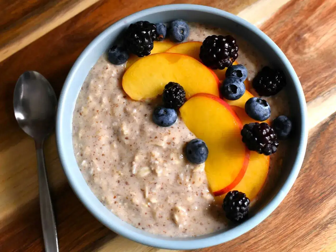Vegane Overnight Oats mit Pfirsichscheiben, Blaubeeren und Brombeeren. Ein gesundes Frühstück, das perfekt für den Morgen ist.
