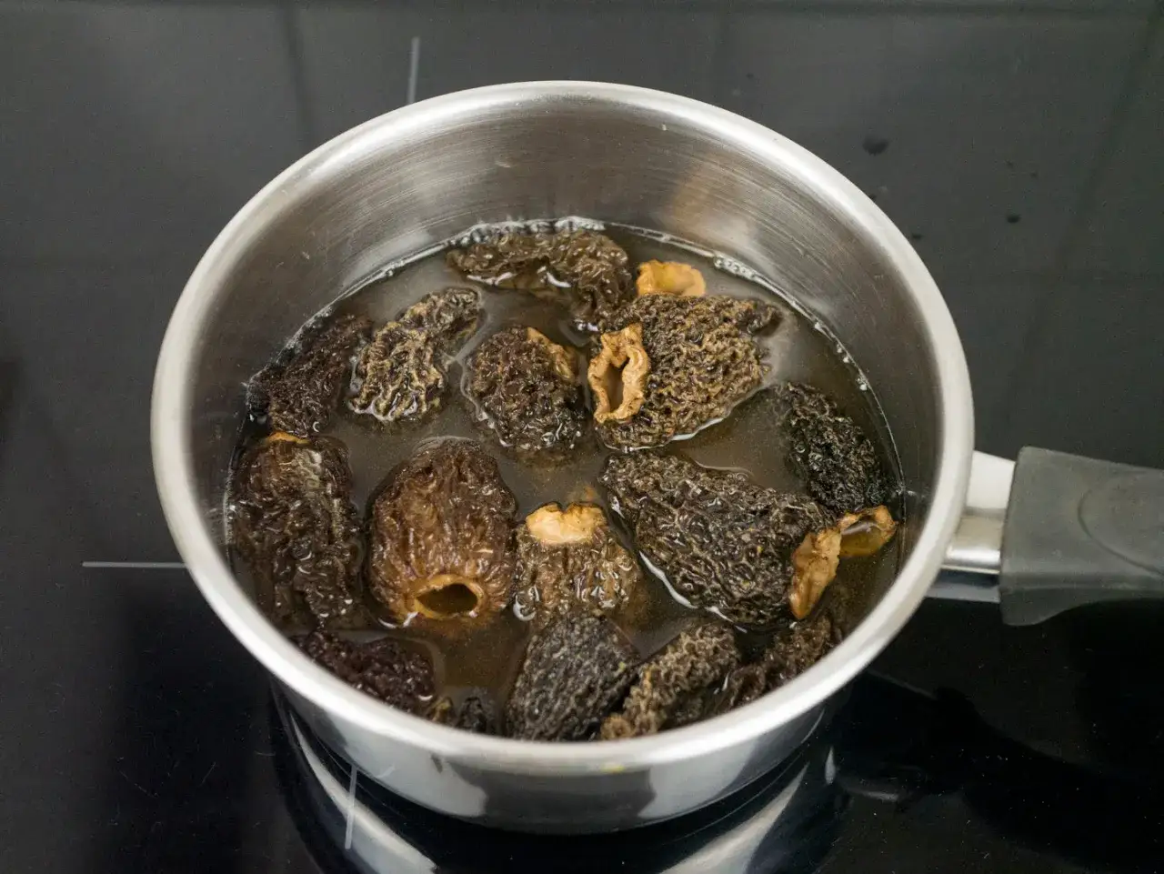 Getrocknete Morcheln werden in einem Topf mit Wasser eingeweicht, um sie f&uuml;r die Zubereitung vorzubereiten.