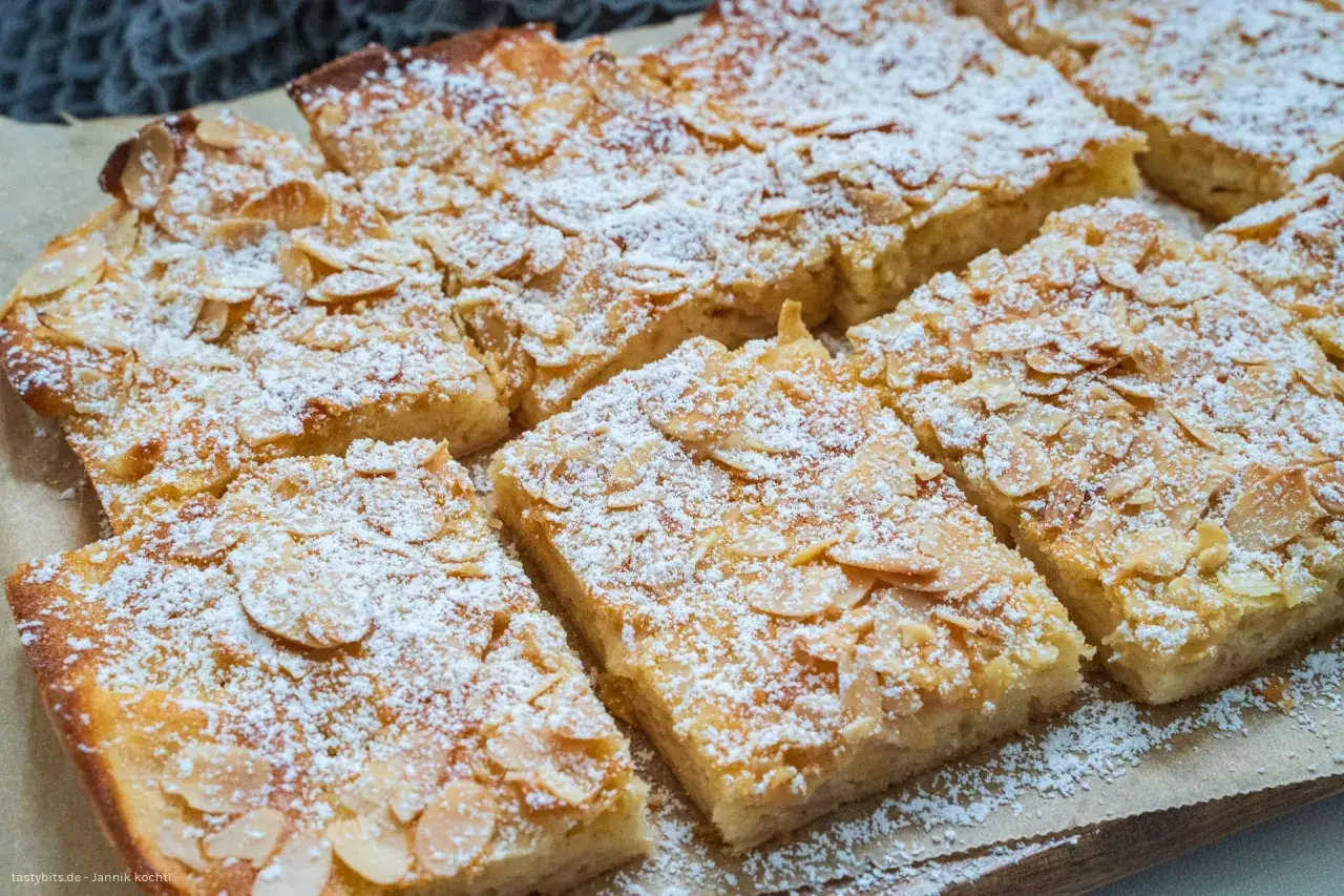 Saftiger Apfelkuchen vom Blech, bestreut mit Puderzucker und Mandelblättchen. Ein Genuss für jeden Anlass!