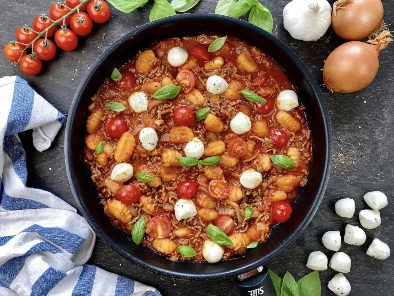 Herzhafte Gnocchi-Rezepte: Gnocchi in Tomatensoße mit Hackfleisch, Mozzarella-Kugeln und frischem Basilikum in einer Pfanne.