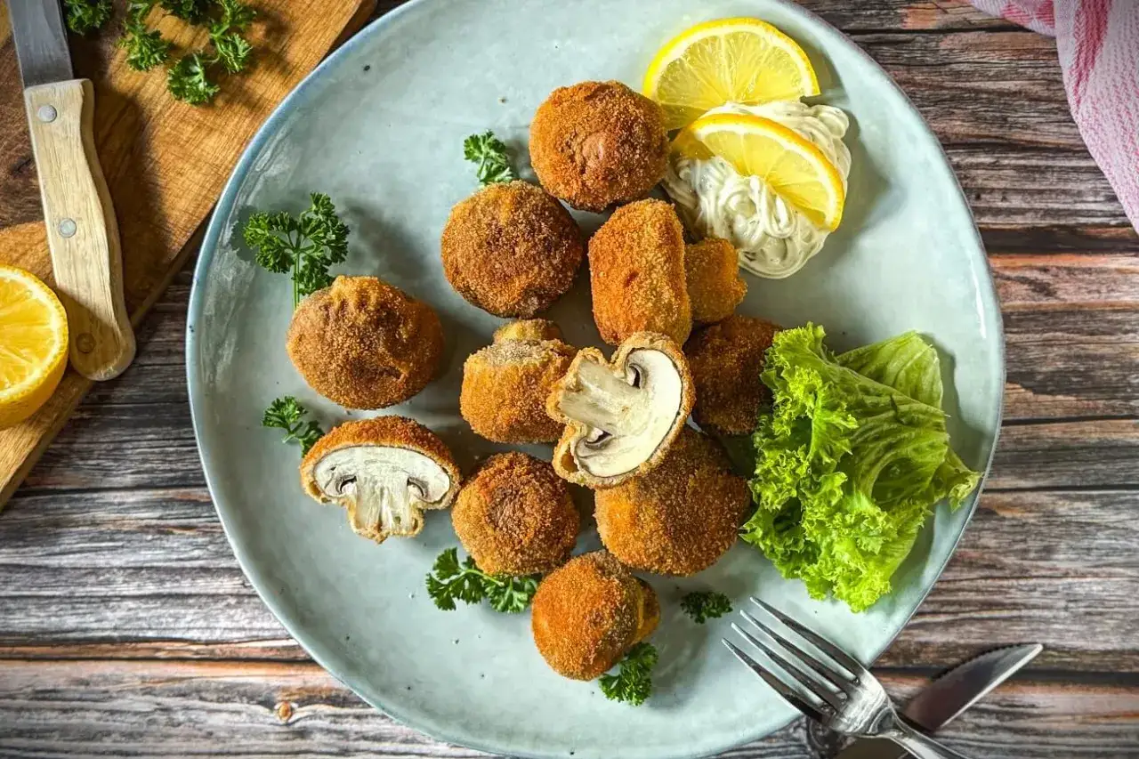 Knusprig gebackene Champignons, garniert mit Zitrone, Mayonnaise und Salat. Ein Genuss f&uuml;r jeden Pilzliebhaber!