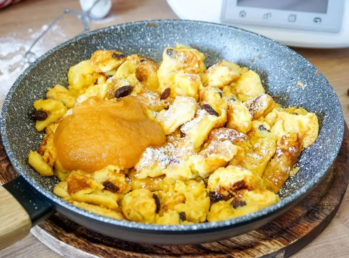 Kaiserschmarrn mit Rosinen und Apfelmus, frisch aus dem Thermomix zubereitet, in einer Pfanne serviert.