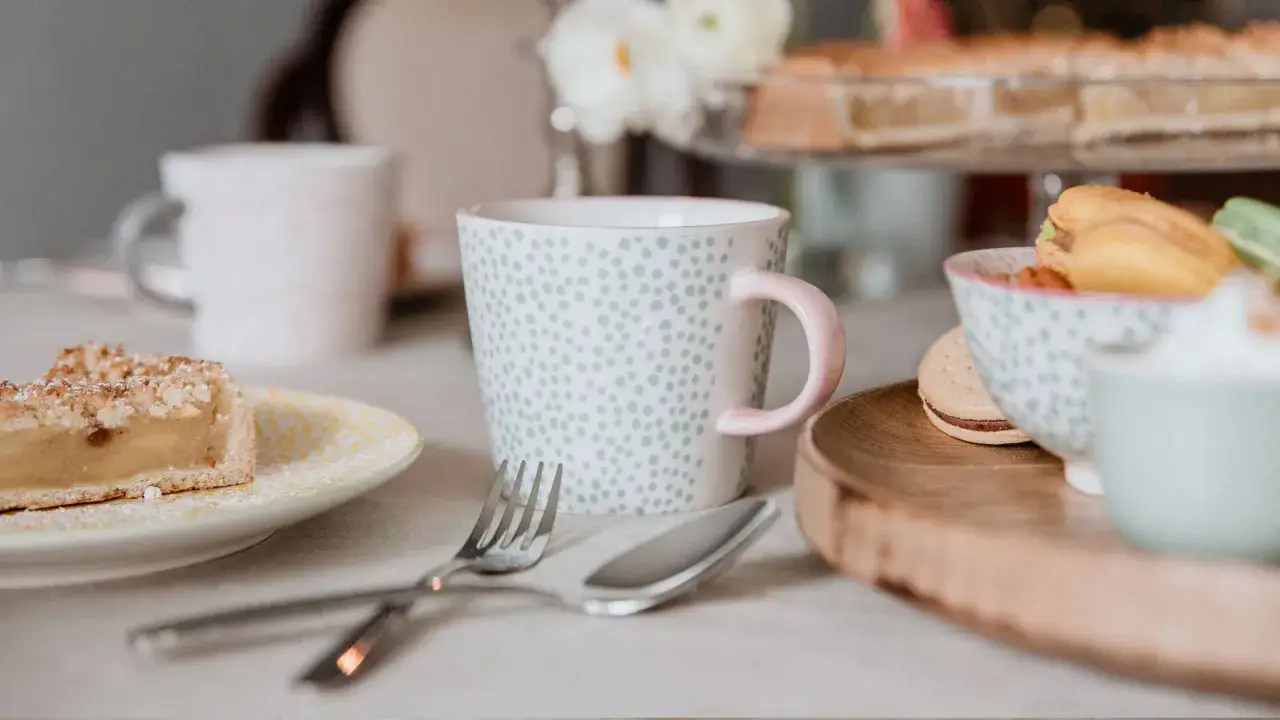 Ein Stück Apfelkuchen, Tassen und Macarons laden zum Genießen ein. Perfekt für gemütliche Stunden mit leckeren Kuchen Rezepten.