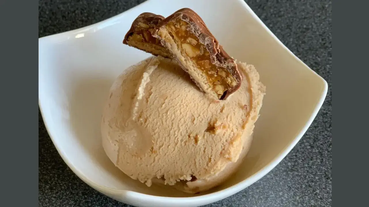 Ein cremiges Snickers Eis selber machen ist einfacher als gedacht! Hier ist das Ergebnis: eine Kugel Eis mit einem St&uuml;ck Snickers obendrauf.