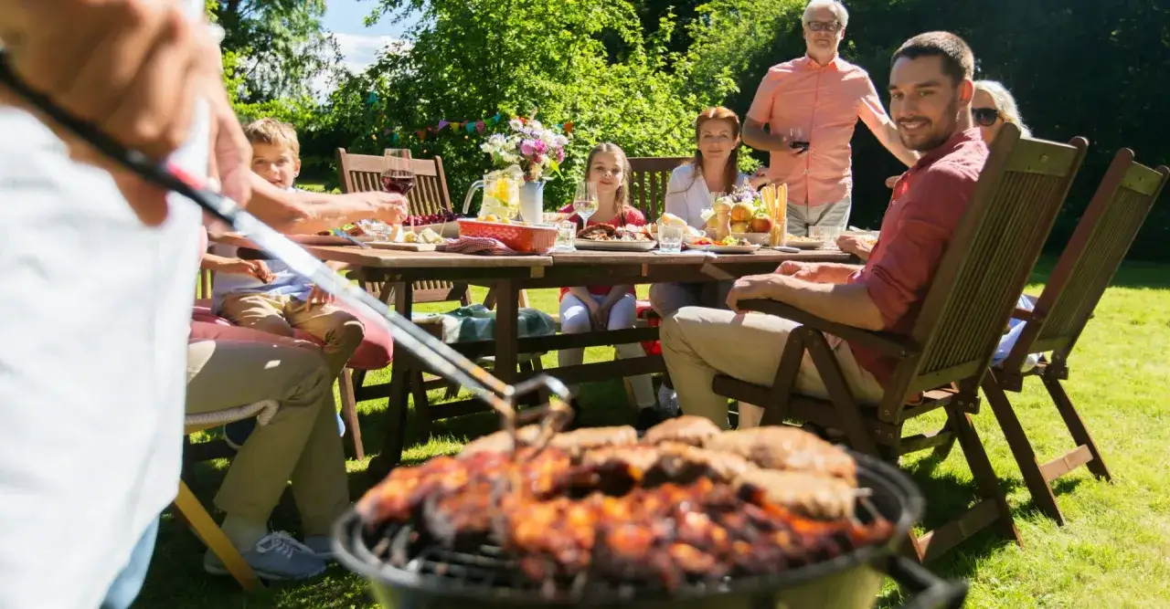 Familie genie&szlig;t ein Sommerfest im Garten. Auf dem Grill brutzeln Leckereien &ndash; so lecker, dass man sich fragt, was kann man grillen!