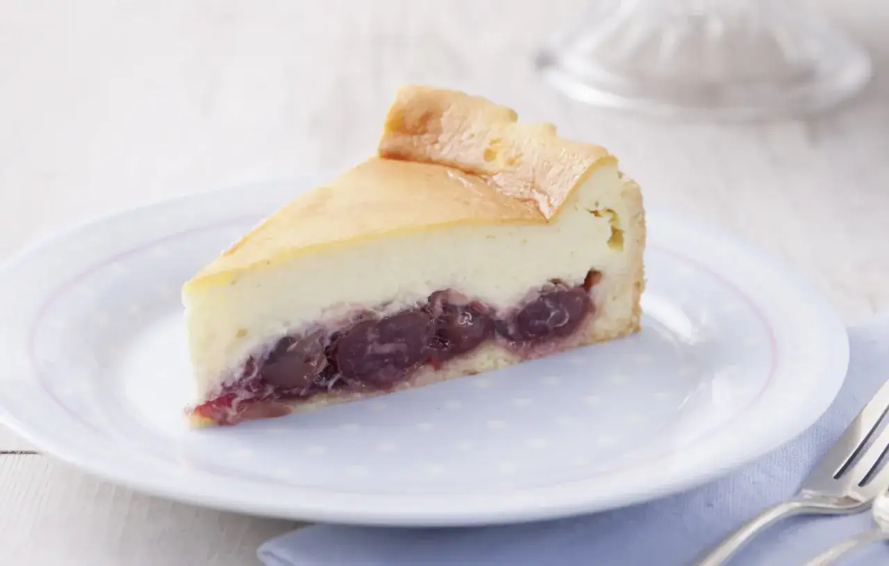 Ein St&uuml;ck Kirsch-Schmand-Kuchen, wie ihn Landfrauen backen, auf einem Teller mit Tupfenmuster.