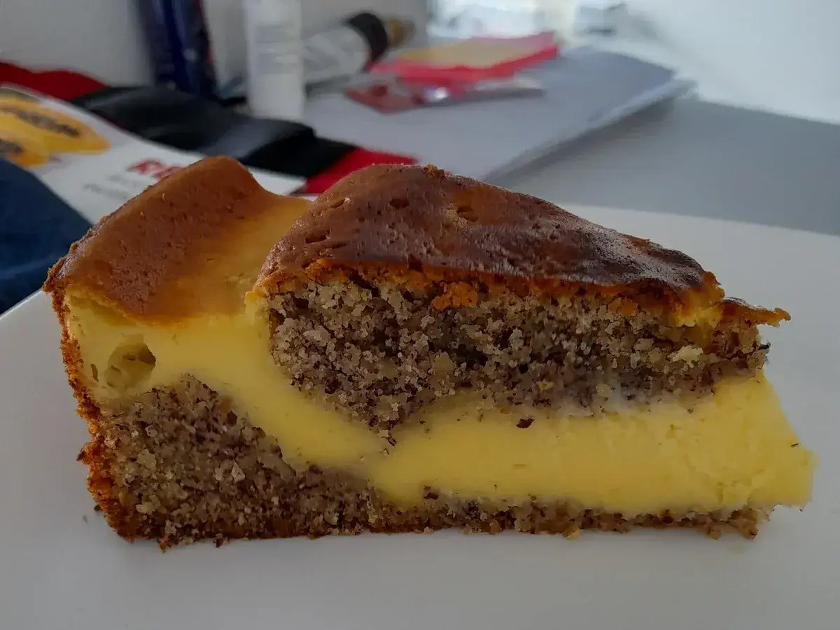 Ein St&uuml;ck nusskuchen mit pudding, mit einer cremigen F&uuml;llung und knusprigem Boden.