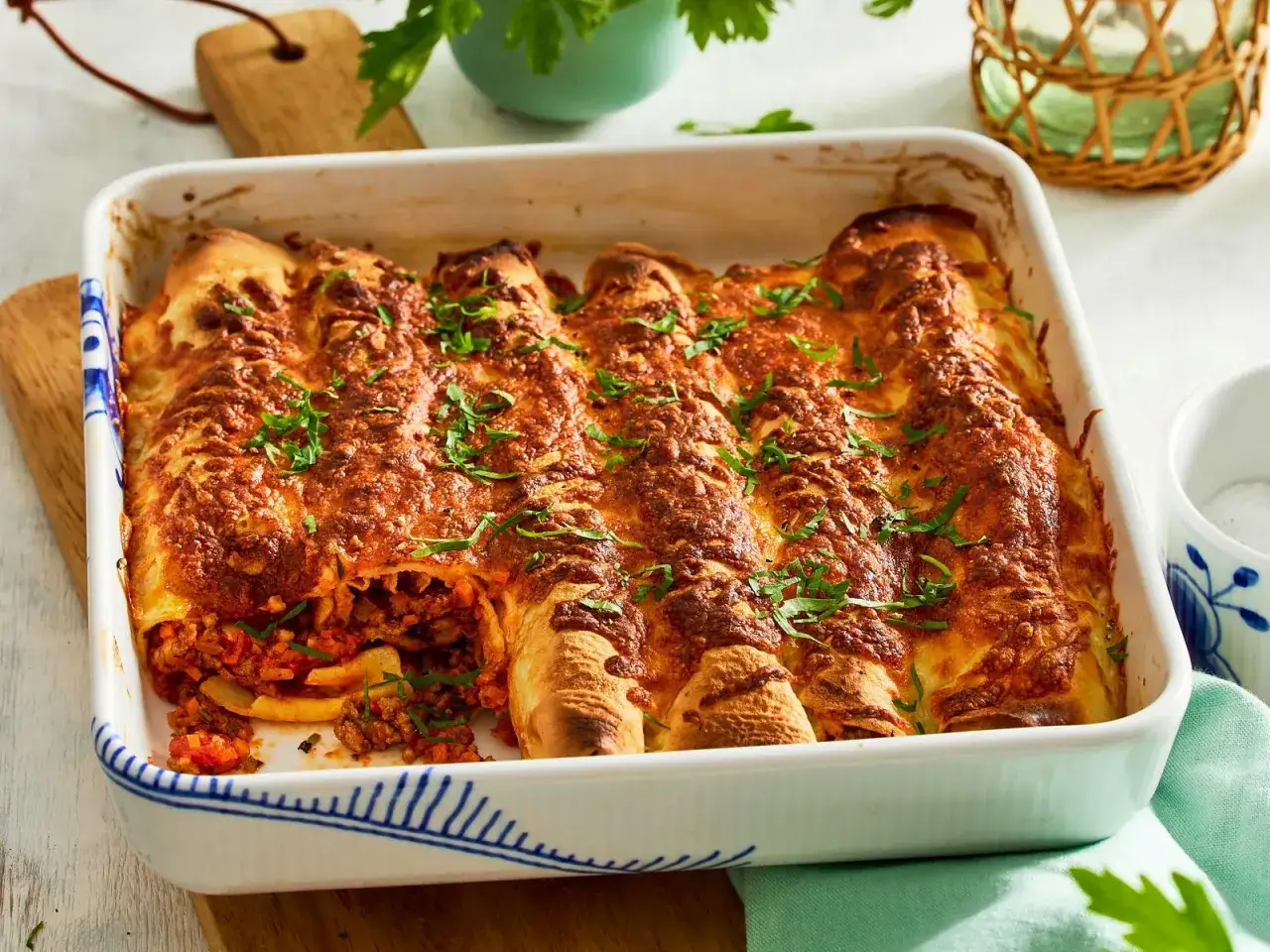Herzhafte Pfannkuchen, gef&uuml;llt mit Hackfleisch und Gem&uuml;se, &uuml;berbacken mit K&auml;se und garniert mit Petersilie, warten in einer Auflaufform auf ihre Verkostung.