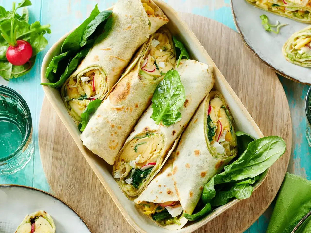 Herzhafte Tortilla-Wraps gef&uuml;llt mit Spinat, Feta und R&uuml;hrei, garniert mit frischem Spinat und Radieschen.