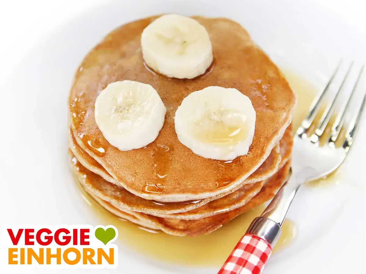Leckere, fluffige bananen pancakes ohne ei, garniert mit Bananenscheiben und Sirup. Ein Traum f&uuml;r jeden Veggie-Fan!