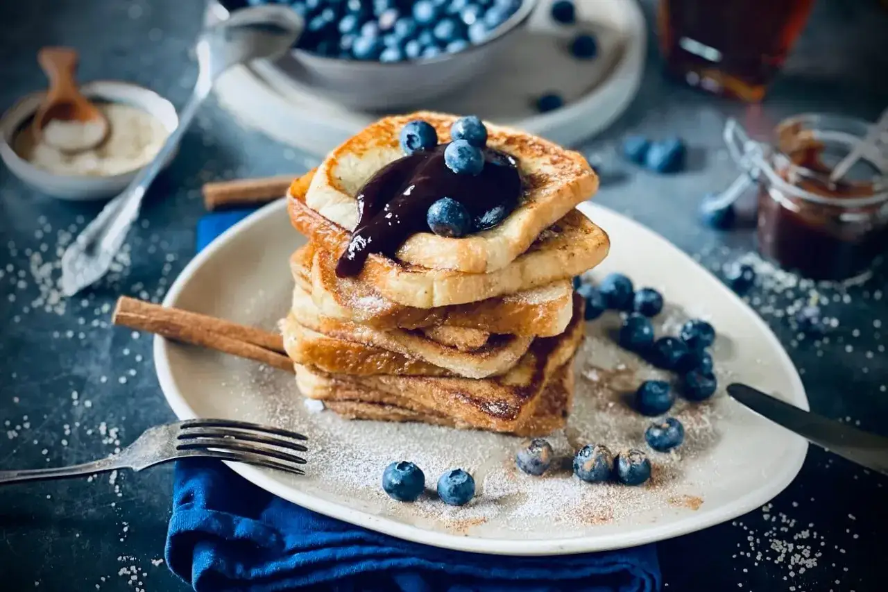 Ein reicher Ritter genie&szlig;t &uuml;ppige French Toast-T&uuml;rme mit Blaubeeren und Schokoladensauce. Der arme Ritter hat nur ein paar Kr&uuml;mel.