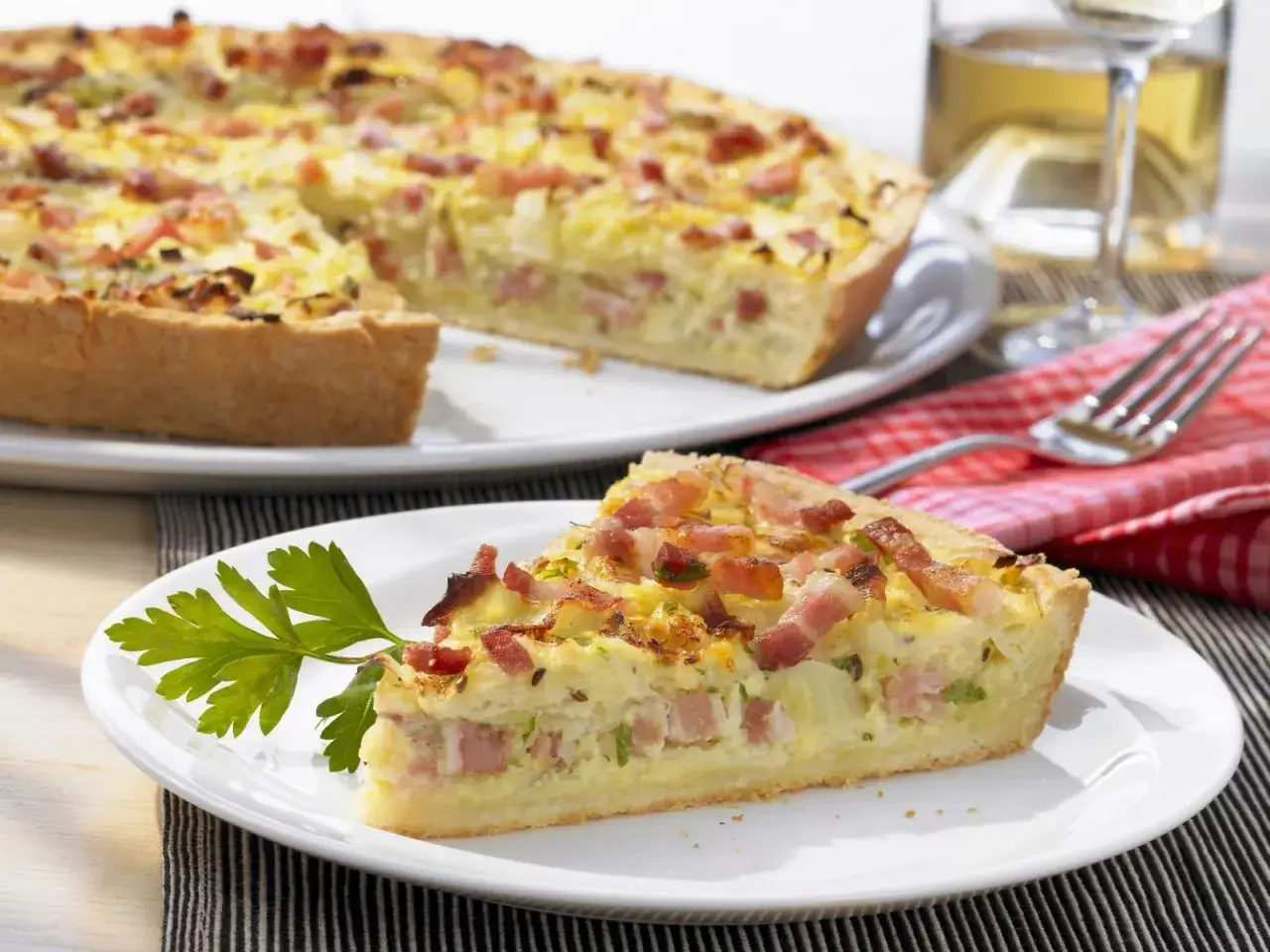Ein Stück herzhafter Speckkuchen, inspiriert von ewiger Kohl Rezepte, auf einem Teller mit Petersilie garniert.