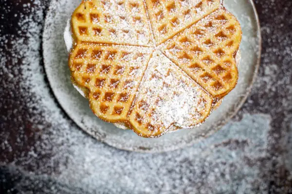 Herzförmige Waffeln, bestäubt mit Puderzucker, sehen aus wie aus einem perfekten Waffeln Rezept.