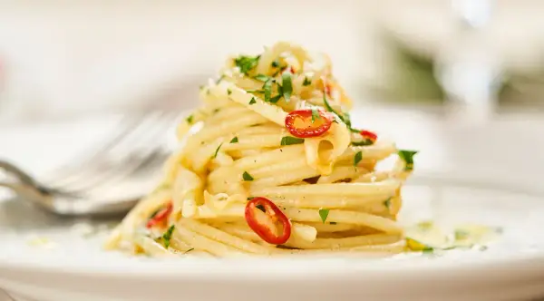 Ein Berg von Spaghetti Aglio e Olio, garniert mit frischer Petersilie und scharfen Chilischeiben.